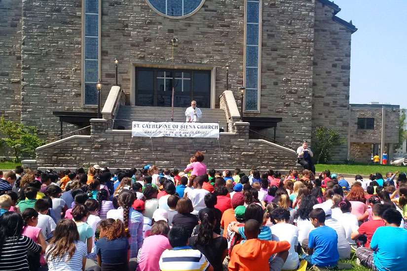 St. Catherine Siena community pray together in front of damaged statue