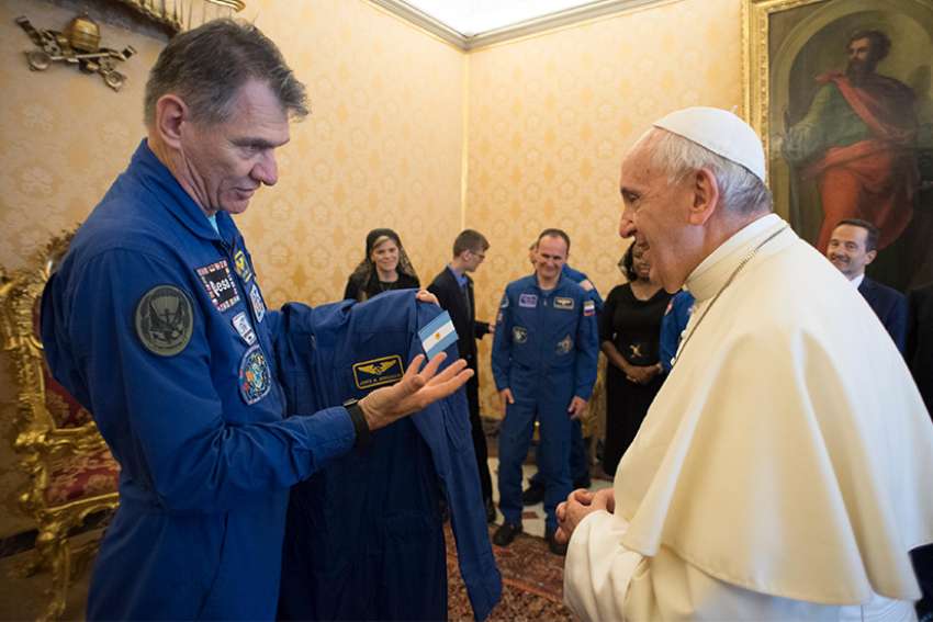 Space station crew members give Pope his own flight suit